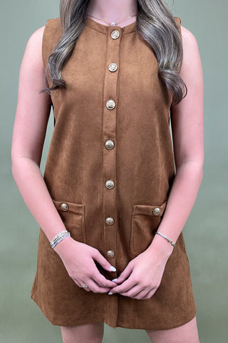 Brown sleeveless dress with button details worn by a person against a neutral background