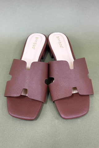 Pair of maroon slides with a heart design on a light gray background