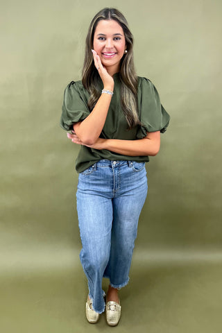 Olive green puff sleeve blouse with split neckline styled with light wash wide leg frayed hem jeans and gold loafers.