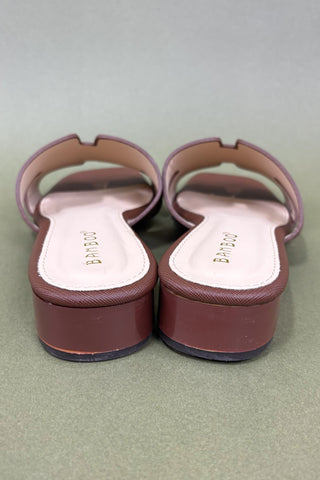 Pair of maroon sandals with white soles on a light gray background