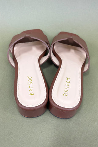 Pair of brown sandals with 'Bamboo' branding on a green background