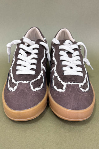 Pair of brown sneakers with white laces on a green background