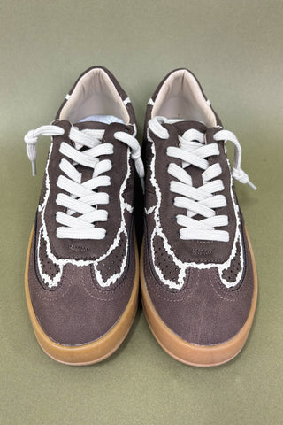 Pair of brown sneakers with white laces on a green background