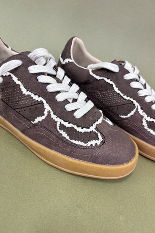 Pair of brown sneakers with white laces on a green background