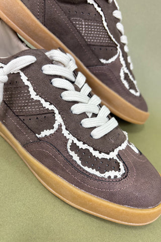 Brown sneakers with white laces and brown soles on a green background