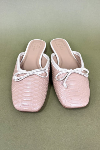 Pair of pink slipper shoes with white laces on a green background