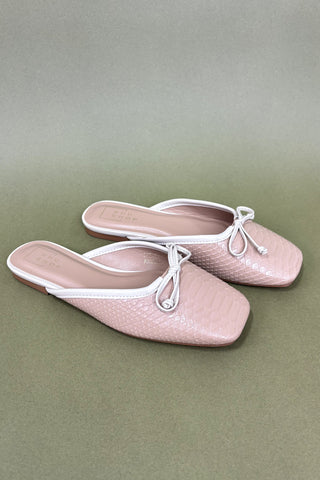 Pair of pink shoes with white laces on a green background