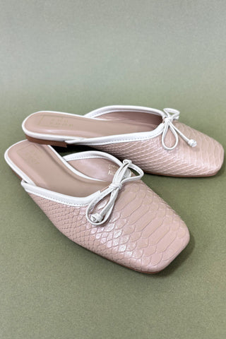 Pair of pink slippers with white laces on a green background