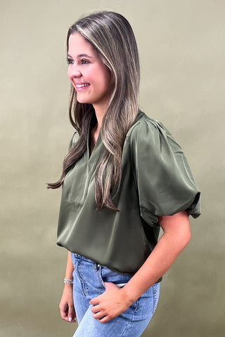 Olive green puff sleeve blouse with split neckline styled with light wash wide leg frayed hem jeans and gold loafers.