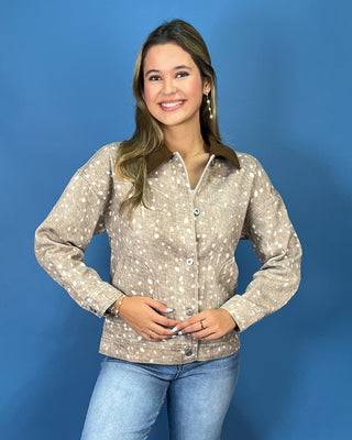 a beige long-sleeve button-up shirt with a white speckled pattern and a brown collar, paired with blue jeans