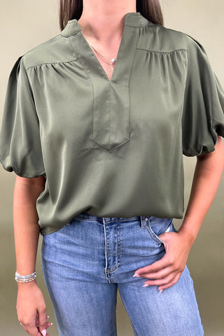 Olive green puff sleeve blouse with split neckline styled with light wash wide leg frayed hem jeans and gold loafers.