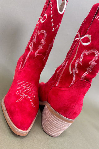 Red cowboy boots with white embroidery on a light gray background
