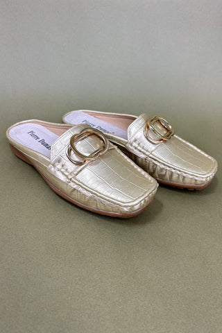 Pair of gold loafers with a buckle on a beige background