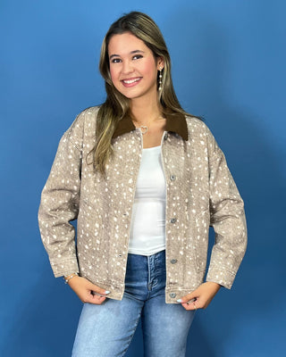  a beige long-sleeve button-up shirt with a white speckled pattern and a brown collar, paired with blue jeans