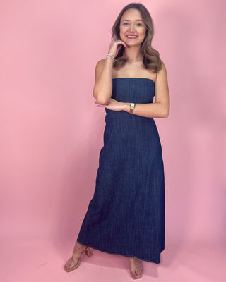 Woman wearing a strapless denim dress against a pink background
