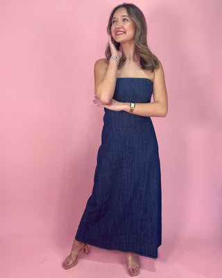 Woman wearing a strapless denim dress against a pink background