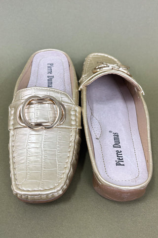 Pair of gold loafers with a decorative buckle on a green background