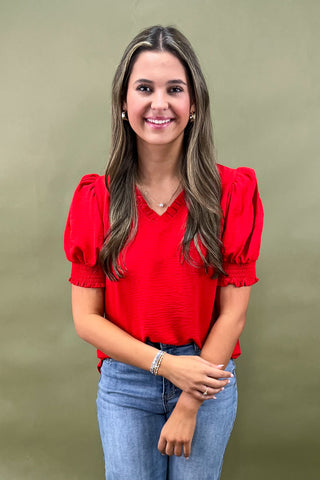 Red puff sleeve blouse with v-neckline styled with light wash wide leg frayed hem jeans and gold loafers.