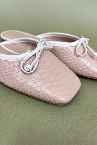 Pair of pink ballet flats with white laces on a green background