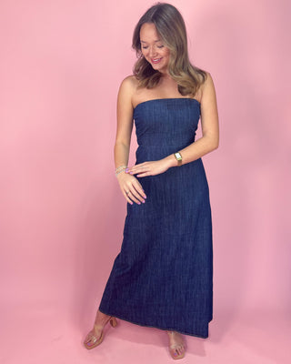 Woman wearing a strapless denim dress against a pink background