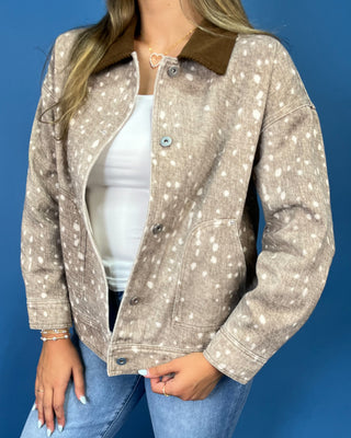  a beige long-sleeve button-up shirt with a white speckled pattern and a brown collar, paired with blue jeans