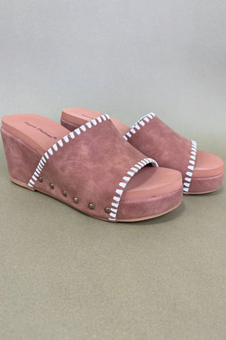 Pair of pink suede sandals with white stitching on a gray background