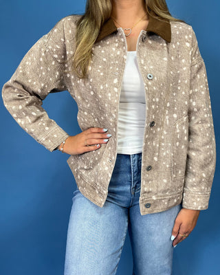  a beige long-sleeve button-up shirt with a white speckled pattern and a brown collar, paired with blue jeans