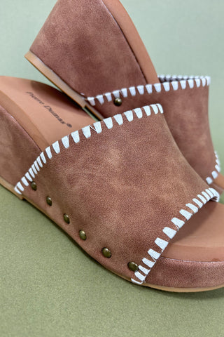 Brown sandals with white trim on a green background
