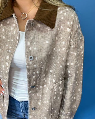  a beige long-sleeve button-up shirt with a white speckled pattern and a brown collar, paired with blue jeans
