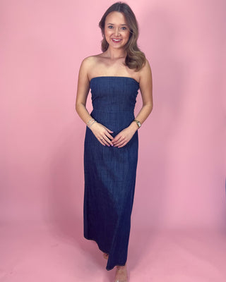 Woman wearing a strapless denim dress against a pink background