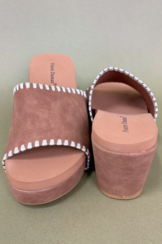 Pair of brown suede sandals with white trim on a light green background