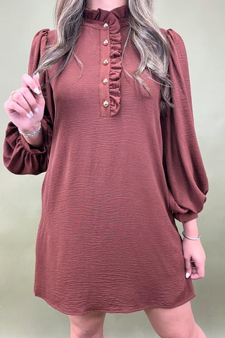 Brown dress with long sleeves worn by a person on a plain background