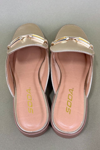 Pair of gold sandals with 'SODA' branding on a gray background