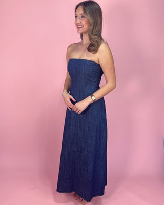 Woman wearing a strapless denim dress against a pink background