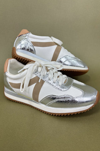 Silver and white sneakers against a beige background