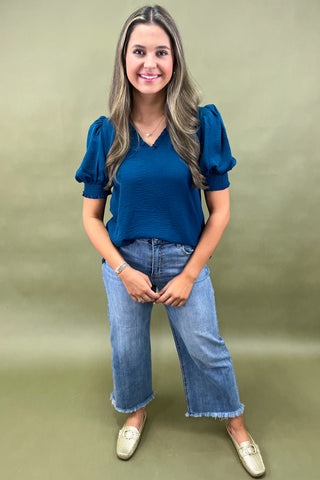Teal puff sleeve blouse with v-neckline styled with light wash wide leg frayed hem jeans and gold loafers