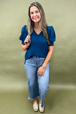 Teal puff sleeve blouse with v-neckline styled with light wash wide leg frayed hem jeans and gold loafers