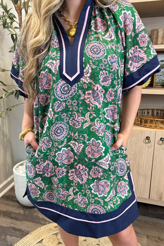 Woman wearing a green floral dress with navy accents in a casual setting.