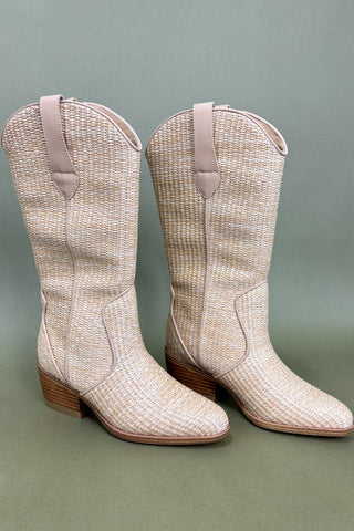 Pair of beige woven cowboy boots on a green background