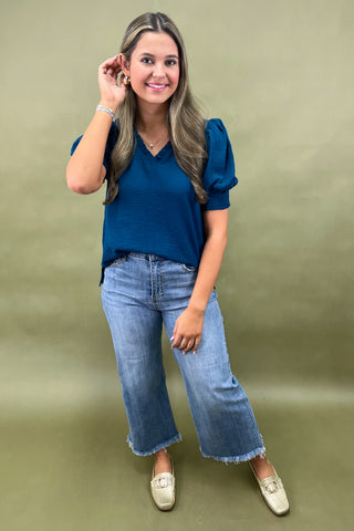 Teal puff sleeve blouse with v-neckline styled with light wash wide leg frayed hem jeans and gold loafers