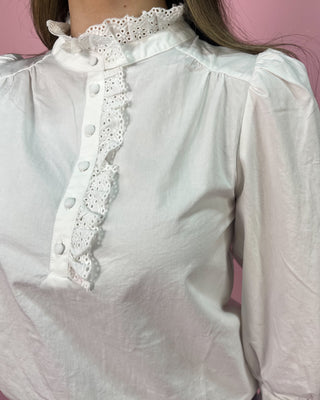 White blouse with lace details on a pink background