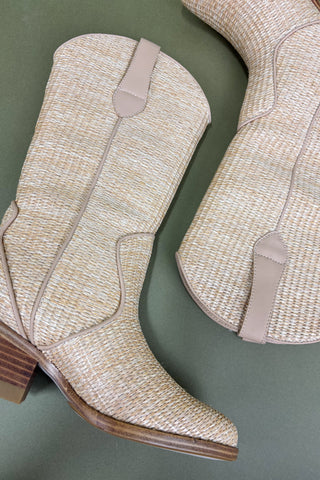 Pair of beige woven cowboy boots on a green background
