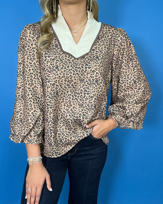 Leopard print blouse with a contrasting cream ruffle collar, three-quarter puff sleeves, and feminine ruffle cuff details.