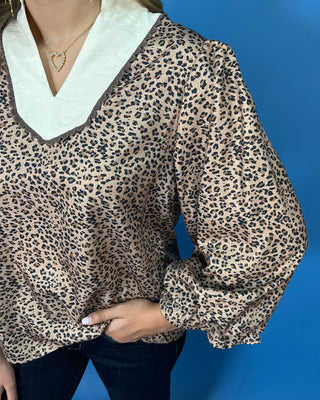 Leopard print blouse with a contrasting cream ruffle collar, three-quarter puff sleeves, and feminine ruffle cuff details.