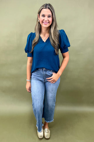 Teal puff sleeve blouse with v-neckline styled with light wash wide leg frayed hem jeans and gold loafers