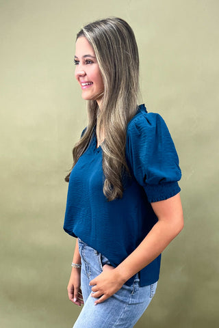 Teal puff sleeve blouse with v-neckline styled with light wash wide leg frayed hem jeans and gold loafers