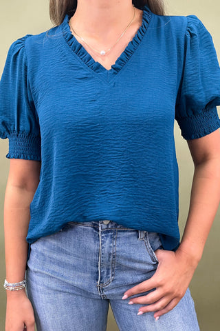 Teal puff sleeve blouse with v-neckline styled with light wash wide leg frayed hem jeans and gold loafers