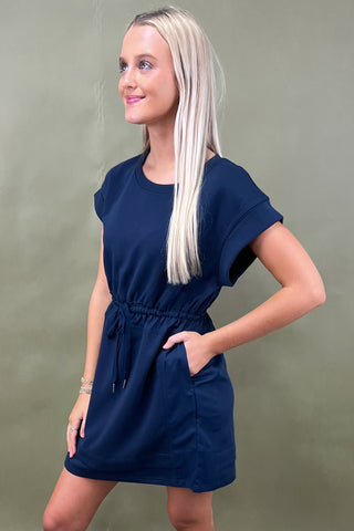 Woman wearing a navy blue dress against a green background