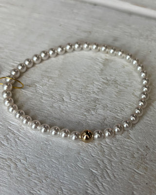 Pearl necklace with a gold clasp on a light wooden surface