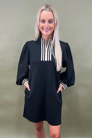 Woman wearing a black dress with striped collar against a green background
